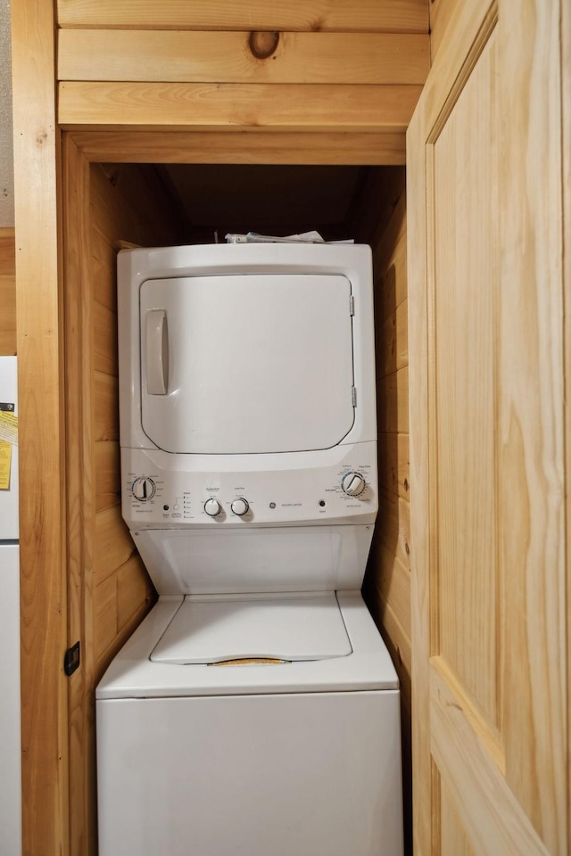 laundry area featuring stacked washer / dryer and wood walls