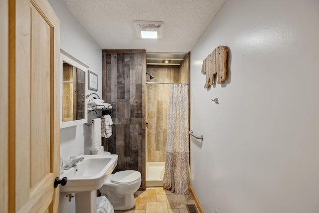 bathroom featuring toilet, sink, a textured ceiling, and a shower with shower curtain