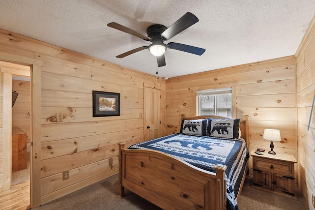 bedroom featuring ceiling fan, a textured ceiling, dark carpet, and wood walls