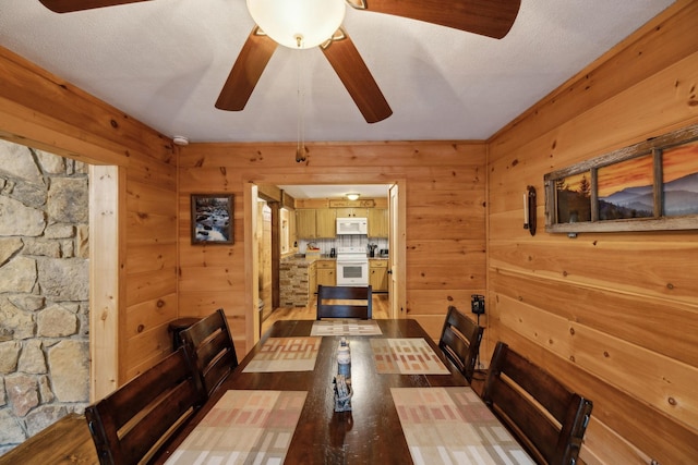 dining room with hardwood / wood-style flooring, ceiling fan, and wooden walls