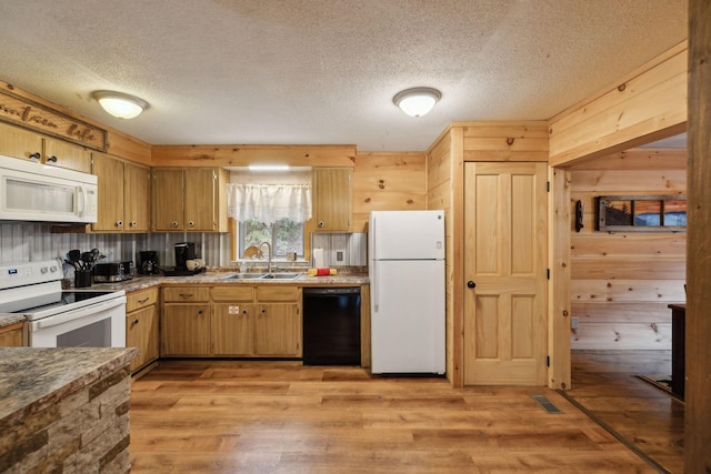 kitchen featuring wooden walls, light wood-type flooring, sink, and white appliances