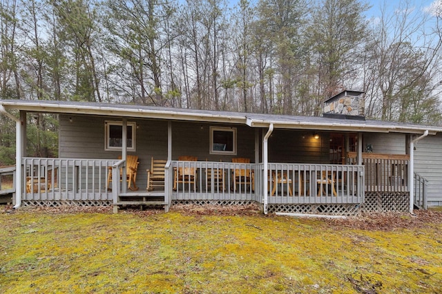 rear view of property featuring a deck and a lawn