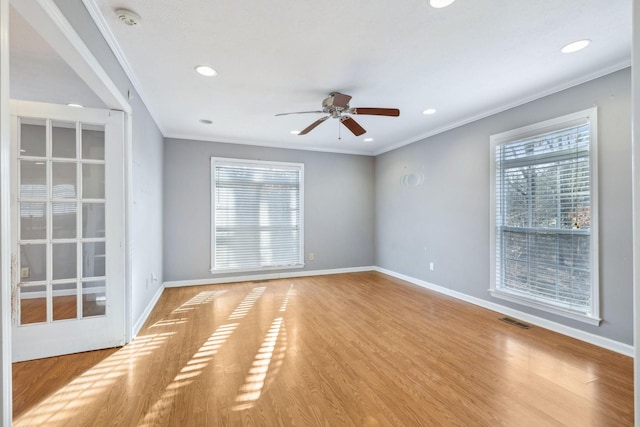 empty room with ornamental molding, a healthy amount of sunlight, ceiling fan, and light wood-type flooring