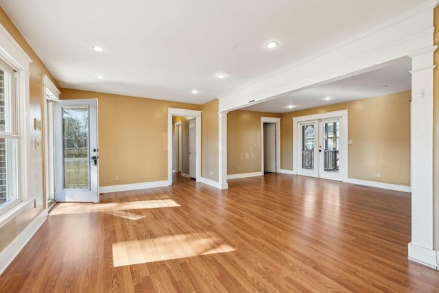 unfurnished living room with light wood-type flooring, french doors, and ornate columns