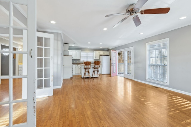 unfurnished living room with ornamental molding, ceiling fan, light hardwood / wood-style floors, and french doors