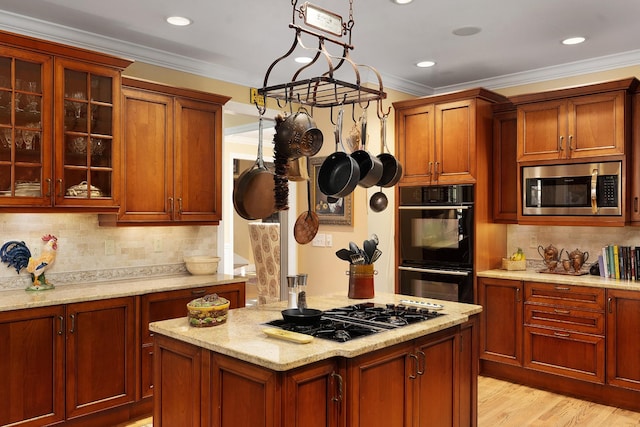 kitchen with hanging light fixtures, ornamental molding, black appliances, light stone countertops, and light hardwood / wood-style flooring