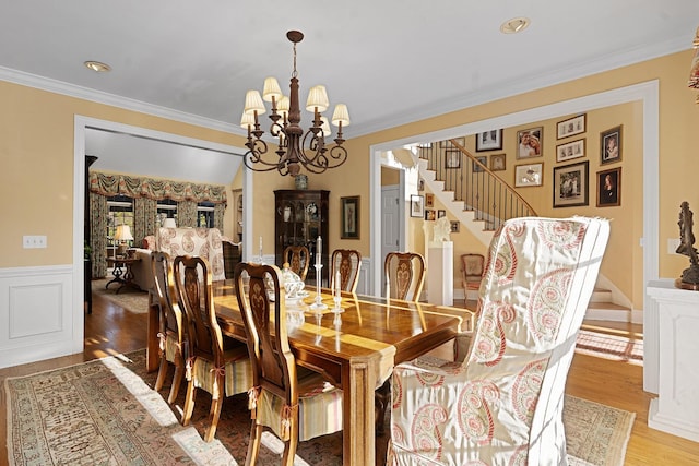 dining area with crown molding, a chandelier, and light wood-type flooring