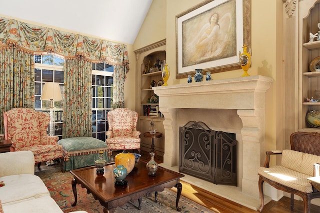 sitting room with lofted ceiling, built in shelves, and wood-type flooring