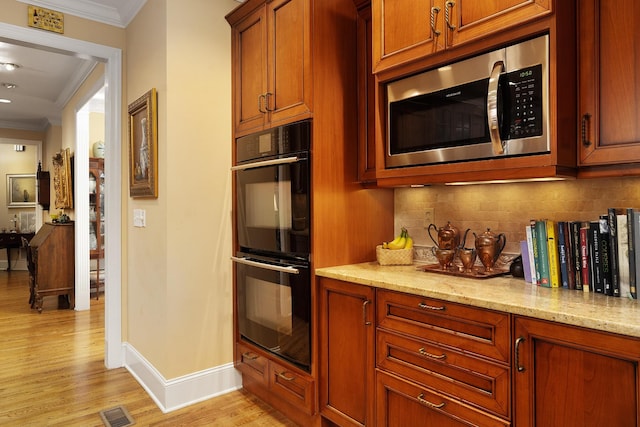 kitchen with backsplash, black double oven, light stone counters, light hardwood / wood-style floors, and crown molding