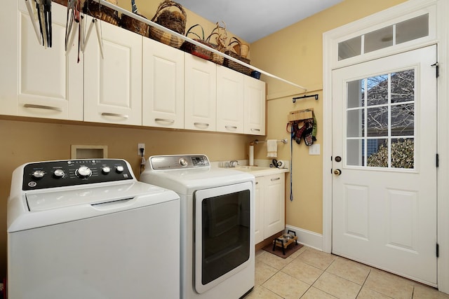 laundry room with cabinets, light tile patterned floors, and washing machine and clothes dryer