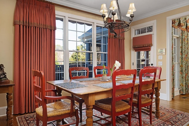 dining area with crown molding, wood-type flooring, and a chandelier