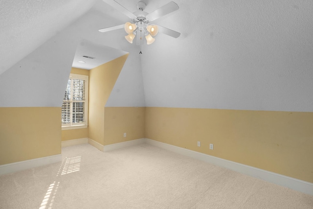 bonus room with lofted ceiling, light colored carpet, and a textured ceiling