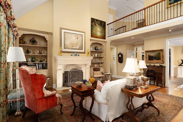 living room with hardwood / wood-style flooring, crown molding, a high ceiling, and built in shelves