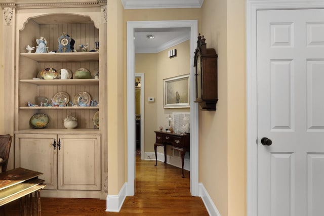 hall featuring crown molding, dark wood-type flooring, and built in features