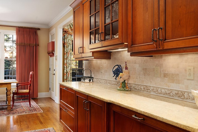 kitchen featuring crown molding, decorative backsplash, light stone counters, and light hardwood / wood-style flooring