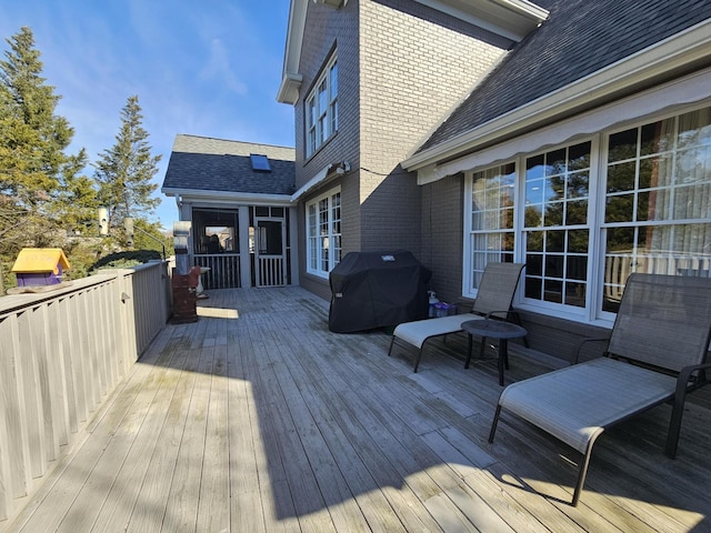 wooden deck with grilling area and a sunroom