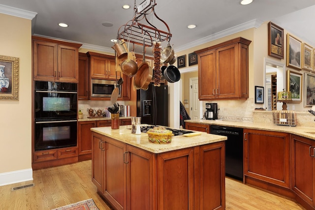 kitchen with crown molding, decorative light fixtures, a kitchen island, and black appliances