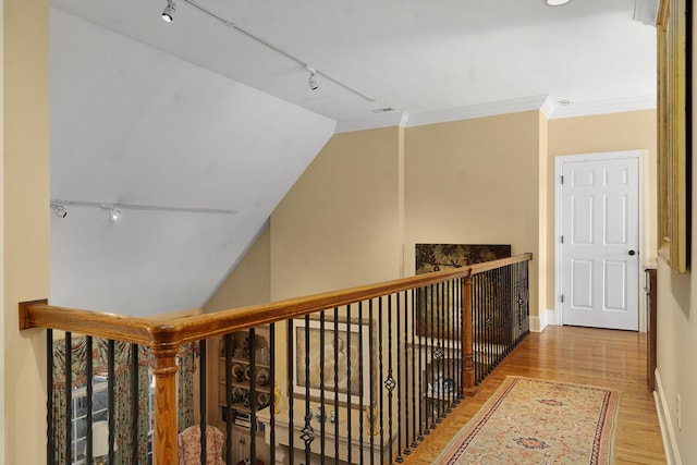 hall featuring light hardwood / wood-style flooring, ornamental molding, and track lighting