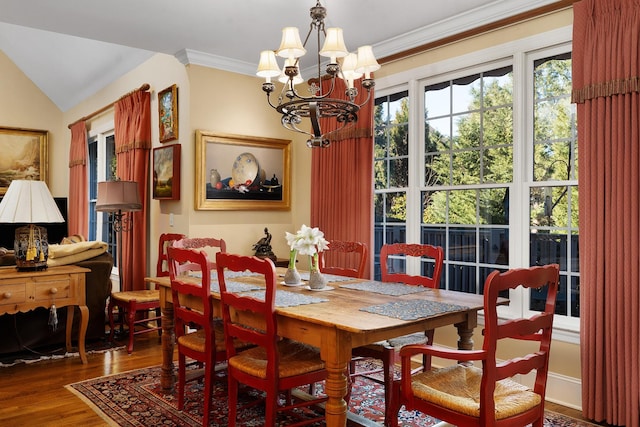 dining space featuring ornamental molding, lofted ceiling, dark wood-type flooring, and an inviting chandelier