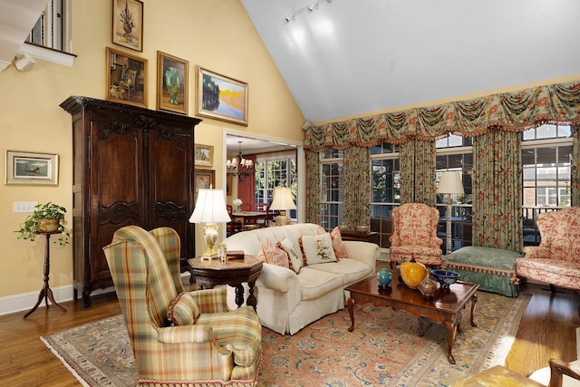 living room featuring hardwood / wood-style flooring, high vaulted ceiling, track lighting, and an inviting chandelier