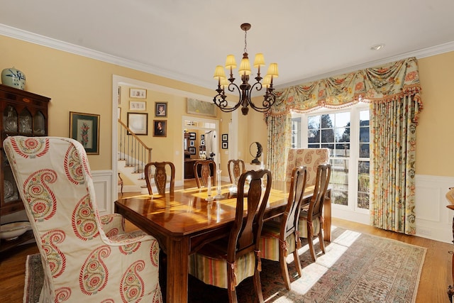 dining area with wood-type flooring, ornamental molding, and a chandelier