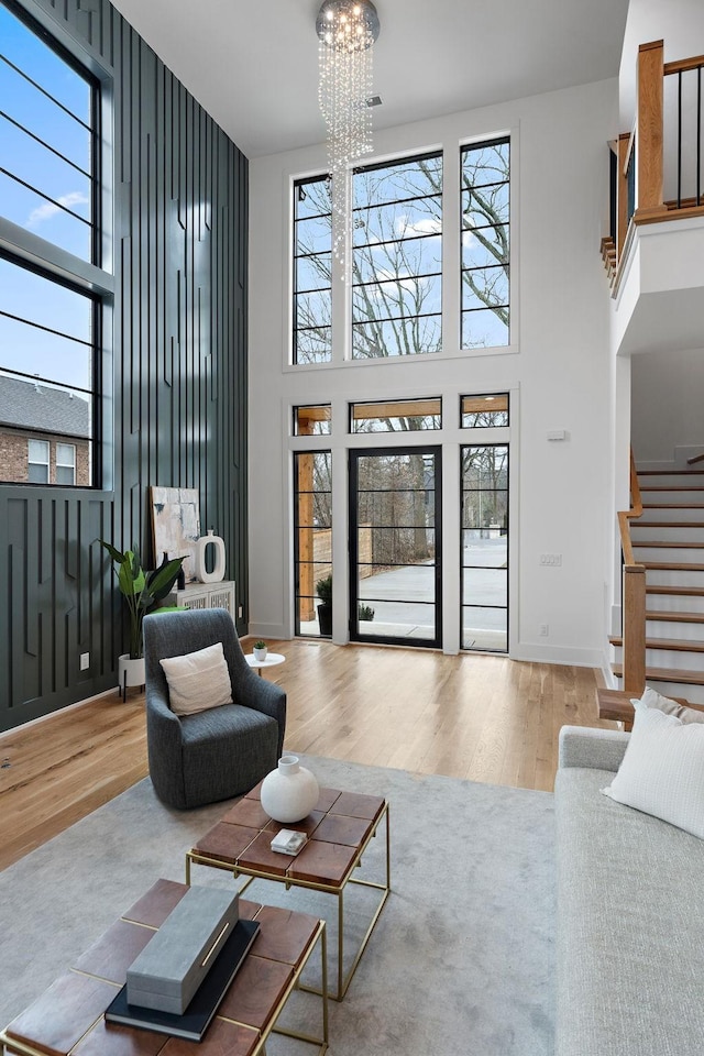 living room featuring a towering ceiling, wood-type flooring, and a chandelier