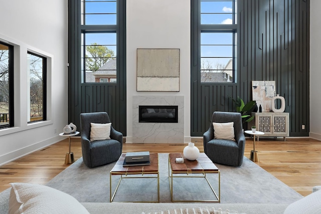 living room with a fireplace, wood-type flooring, and a high ceiling