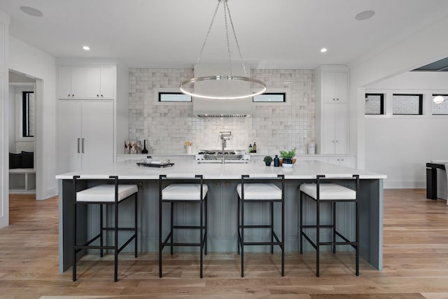 kitchen featuring white cabinetry, a breakfast bar, and a large island with sink