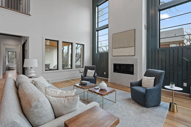 living room with hardwood / wood-style flooring, a premium fireplace, and a high ceiling