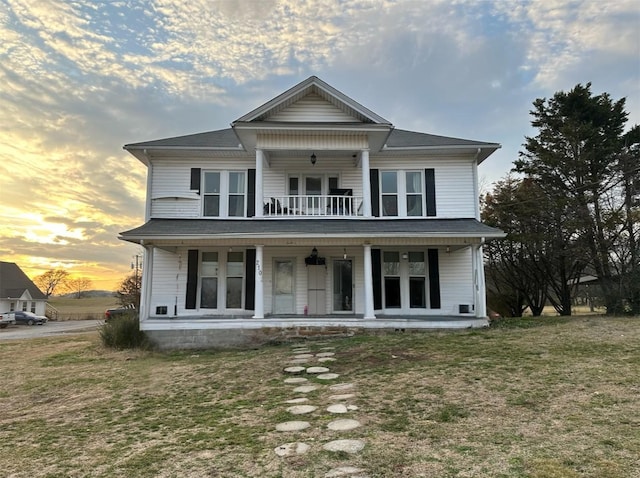 view of front of home featuring french doors, covered porch, and a lawn