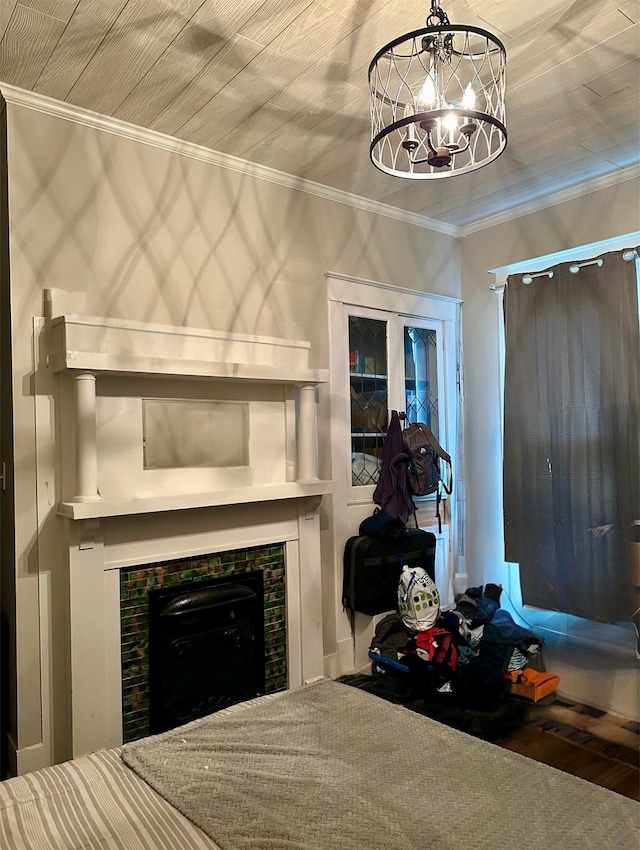 bedroom featuring a tiled fireplace, ornamental molding, and a notable chandelier