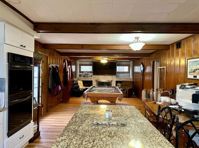 kitchen featuring beamed ceiling, light stone countertops, and white cabinets