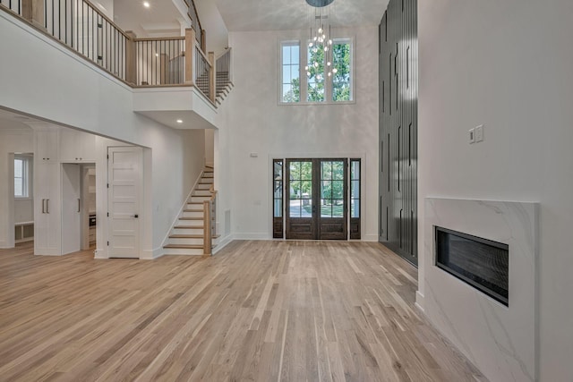 unfurnished living room featuring french doors, light hardwood / wood-style floors, and a notable chandelier