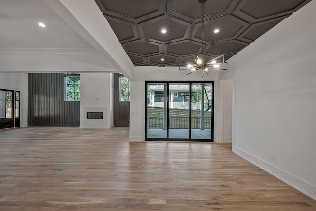 interior space with an inviting chandelier, coffered ceiling, and light hardwood / wood-style floors