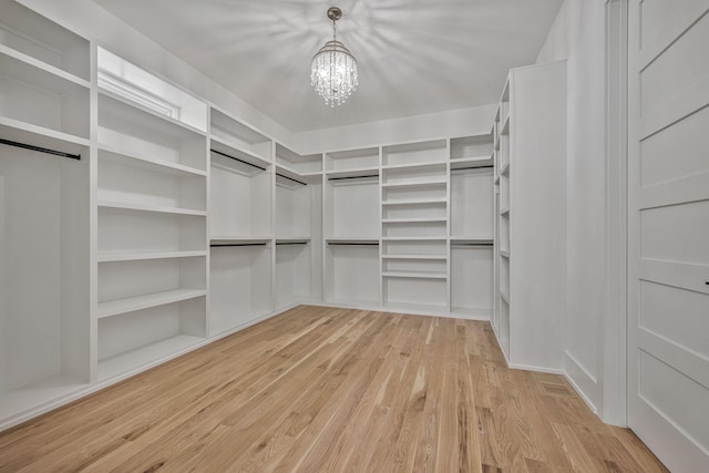 walk in closet with light hardwood / wood-style flooring and a chandelier