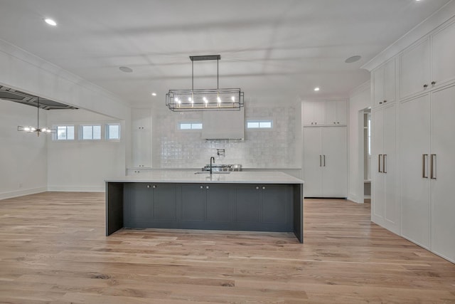 kitchen with white cabinetry, ornamental molding, light hardwood / wood-style flooring, and pendant lighting