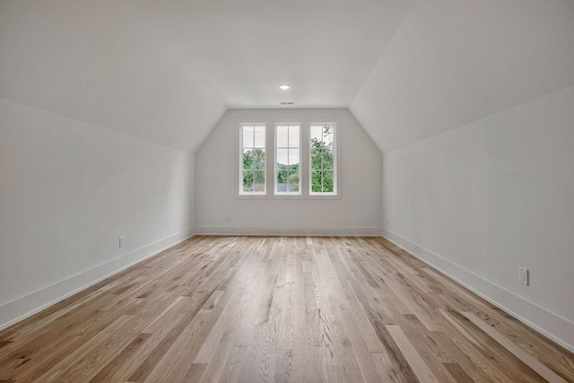 additional living space featuring vaulted ceiling and light wood-type flooring