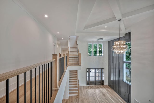 hallway featuring coffered ceiling, an inviting chandelier, light wood-type flooring, a towering ceiling, and beam ceiling