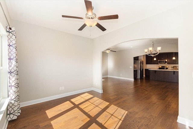 unfurnished living room featuring ceiling fan with notable chandelier and dark hardwood / wood-style flooring