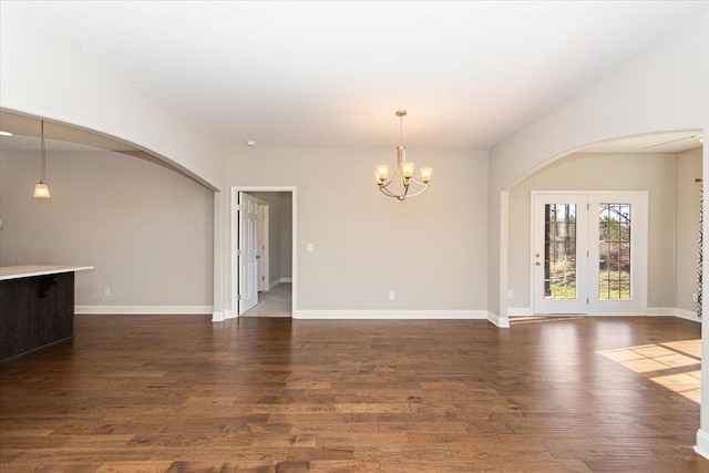 empty room with dark hardwood / wood-style flooring and a chandelier