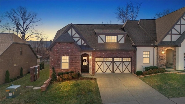 english style home with a garage and a lawn