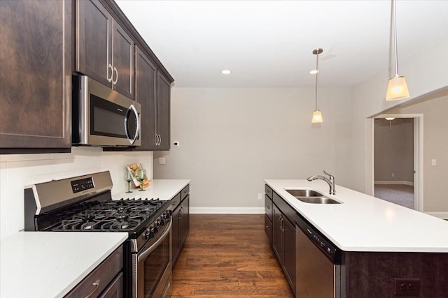 kitchen with sink, appliances with stainless steel finishes, hanging light fixtures, dark hardwood / wood-style floors, and dark brown cabinetry