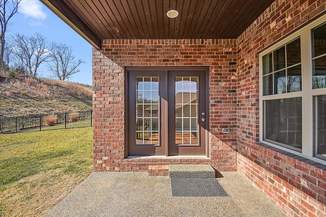 entrance to property with a lawn, a patio, and french doors