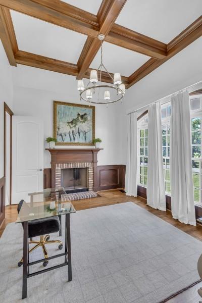 interior space with coffered ceiling, a brick fireplace, beam ceiling, and a chandelier