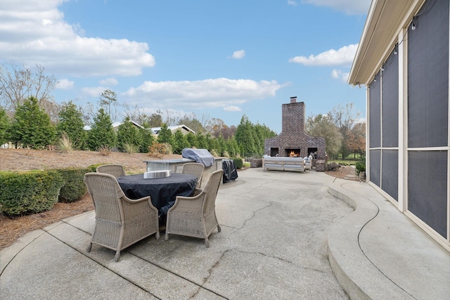 view of patio with exterior fireplace and a grill