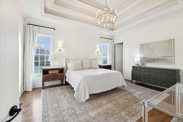 bedroom featuring an inviting chandelier, a tray ceiling, wood-type flooring, and ornamental molding