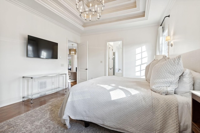 bedroom with ornamental molding, hardwood / wood-style floors, a chandelier, and a tray ceiling