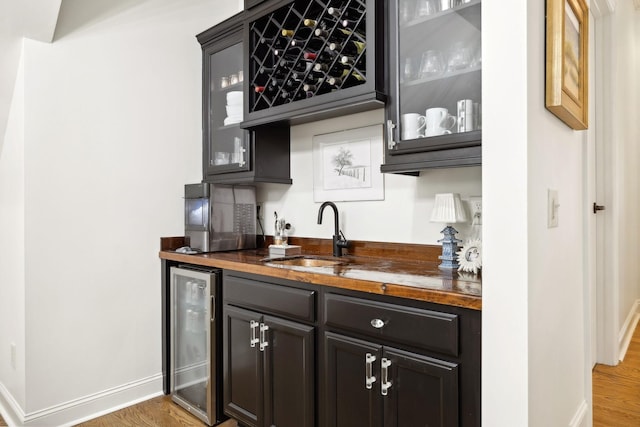 bar featuring dark hardwood / wood-style floors, beverage cooler, butcher block counters, and sink