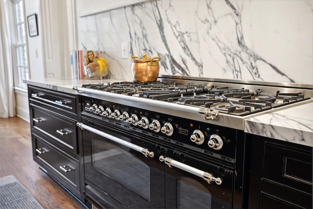 details with double oven range, light stone countertops, dark hardwood / wood-style floors, and backsplash