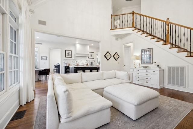 living room featuring hardwood / wood-style floors, ornamental molding, and a high ceiling